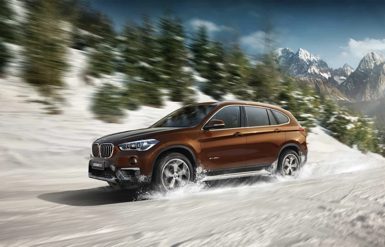 Bronze BMW X1 long-wheelbase model in a snowy mountain scene, 2016 manufacturer promotional reference